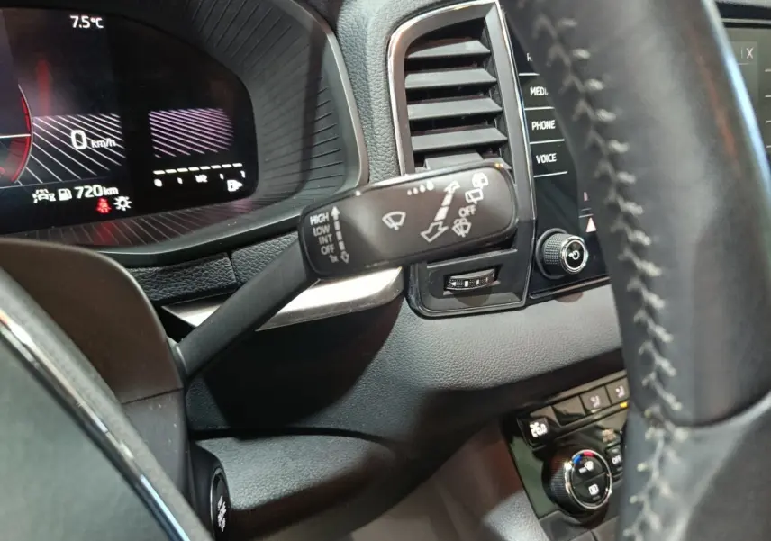 Gros plan sur le combiné d'instruments et la commande d'essuie-glace à gauche du volant cuir dans un Skoda Karoq blanc 2024.