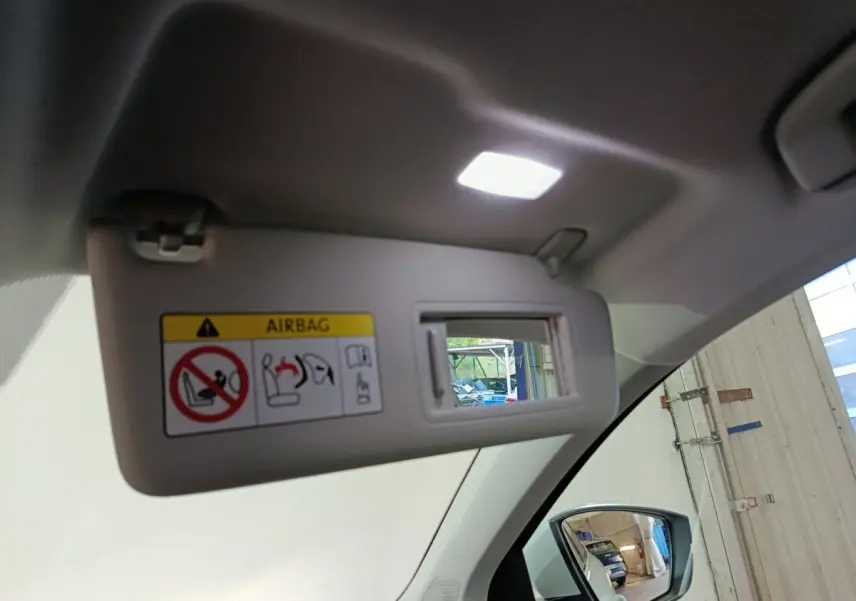 Vue intérieure du pare-soleil côté conducteur avec miroir éclairé et rétroviseur extérieur droit d’un Skoda Karoq blanc 2024.