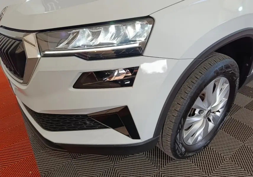 Gros plan sur l’avant droit du Skoda Karoq blanc, mettant en valeur le phare LED et la roue avec jante argentée.