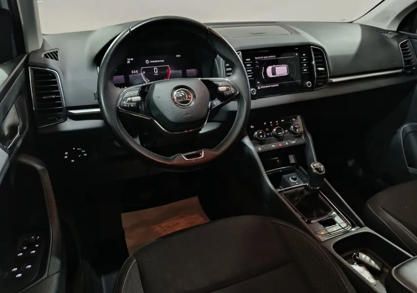 Vue intérieure avant du tableau de bord noir du Skoda Karoq 2024 avec volant cuir et écran tactile central.