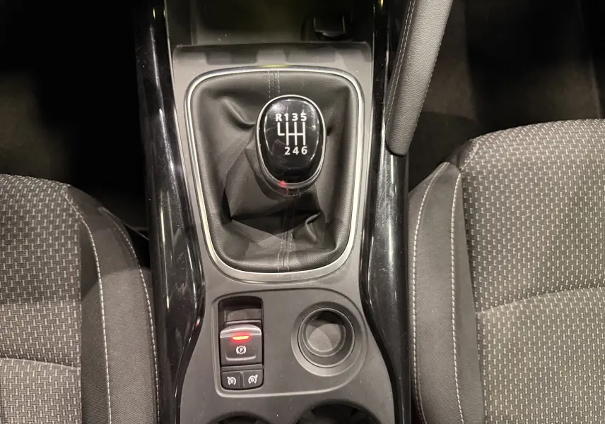Vue intérieure centrée sur la console centrale noire avec frein à main électronique et sièges tissu gris du Renault Kadjar blanc.