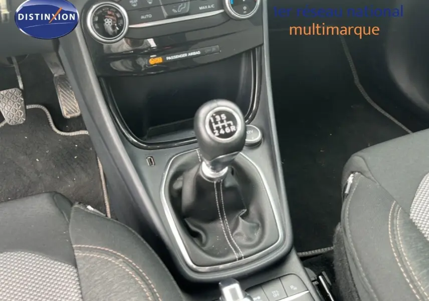 Gros plan sur la console centrale du Ford Puma gris 2021, mettant en valeur la boîte manuelle et les sièges tissu noirs.