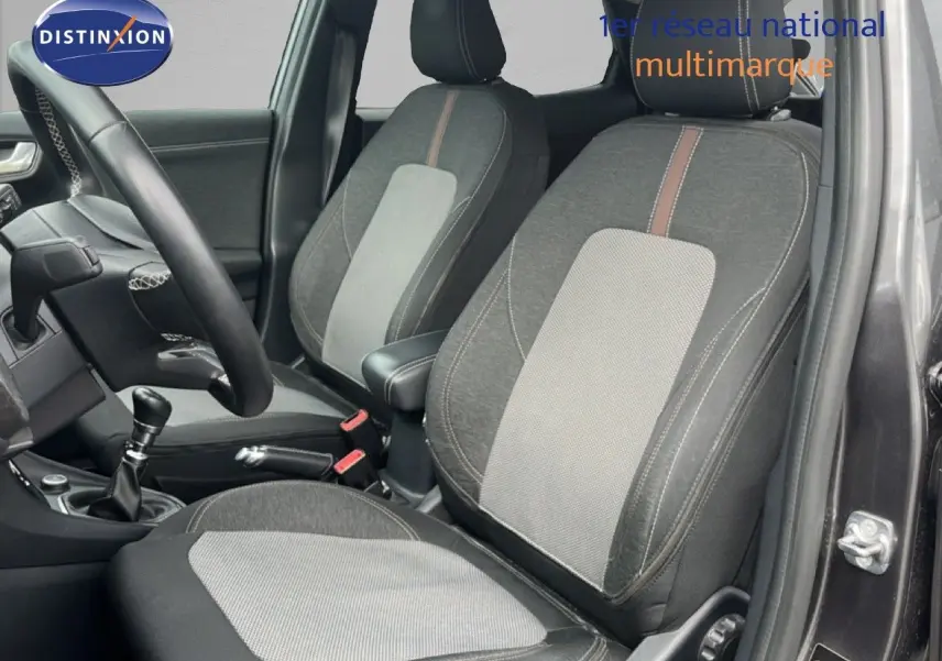 Vue intérieure côté conducteur du Ford Puma gris 2021, montrant les sièges bi-matière et la boîte manuelle.