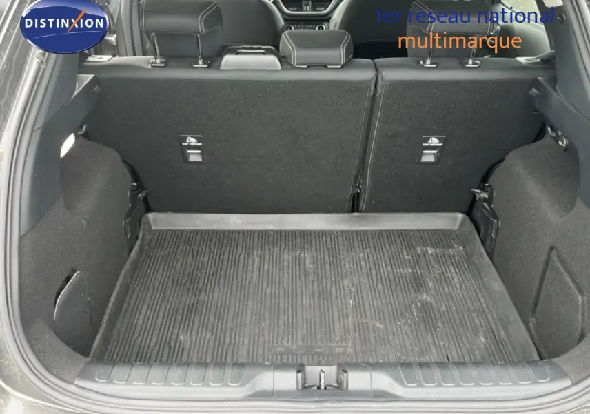 Vue arrière du coffre ouvert du Ford Puma gris 2021, montrant le tapis de sol en caoutchouc et les dossiers de sièges rabattables.