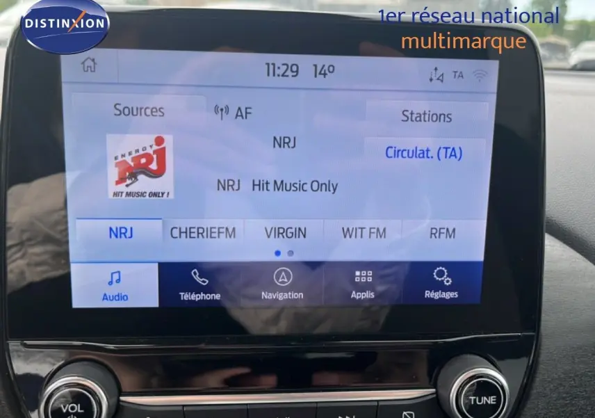 Vue intérieure centrée sur l'écran multimédia du Ford Puma gris 2021 avec interface radio NRJ affichée.