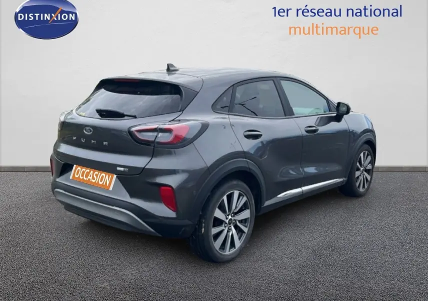 Vue 3/4 arrière droite d’un Ford Puma gris 2021 avec jantes alliage et badge Titanium visible sur le hayon.