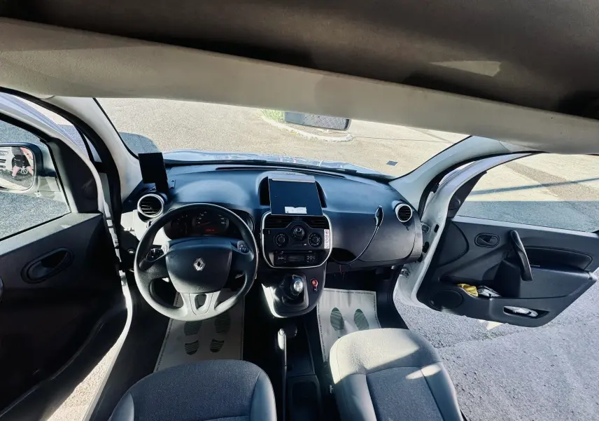 Vue intérieure avant du Renault Kangoo blanc 2021, avec portes ouvertes et tableau de bord noir.