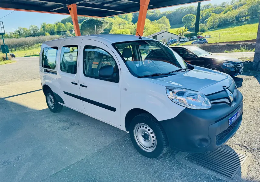 Renault Kangoo Maxi blanc en 3/4 avant droit sous abri, avec pare-chocs noir et jantes acier simples.
