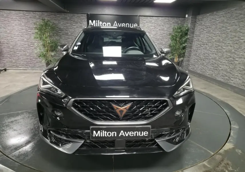 Vue frontale d'un CUPRA Formentor noir Minuit 2023 avec calandre marquée et logo cuivre, dans un showroom intérieur.
