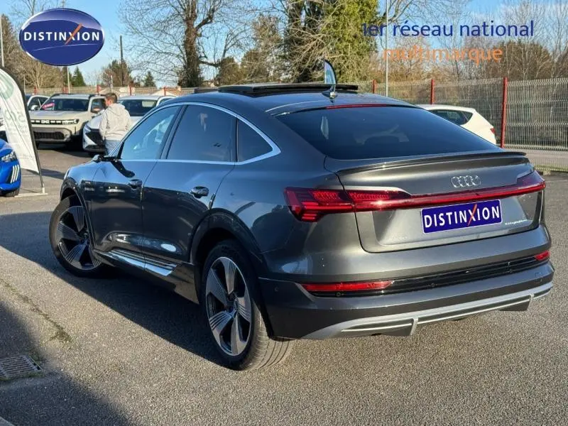 Audi E-Tron Sportback gris foncé métal vue 3/4 arrière droit, avec feux arrière LED et vitres teintées.