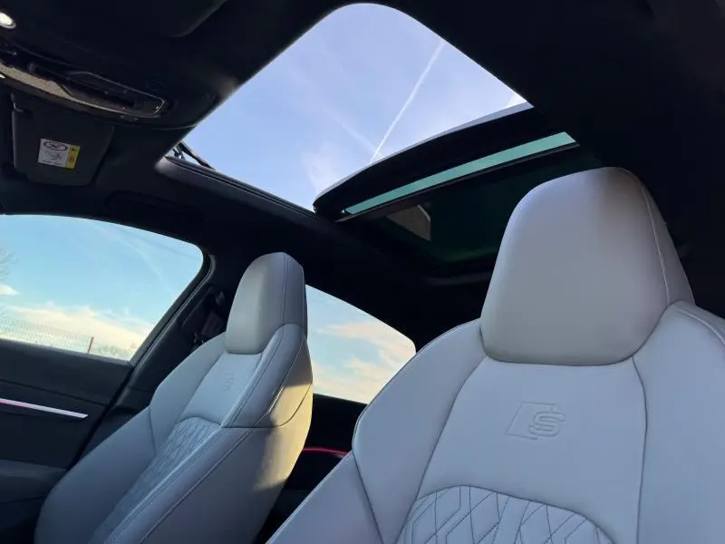 Vue intérieure avant des sièges sport gris clair de l'Audi E-Tron Sportback avec toit ouvrant panoramique ouvert.