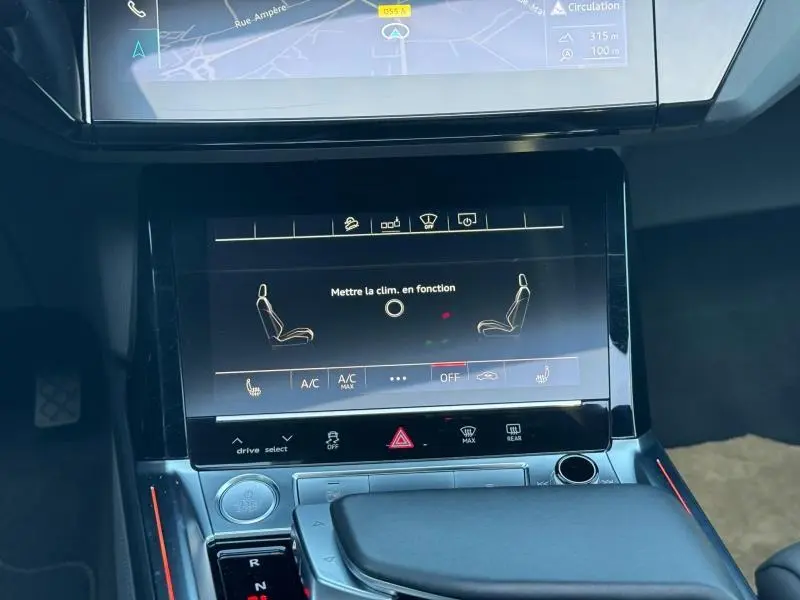 Vue rapprochée de l’écran tactile central du tableau de bord de l’Audi E-Tron Sportback gris foncé, affichant les réglages de climatisation.
