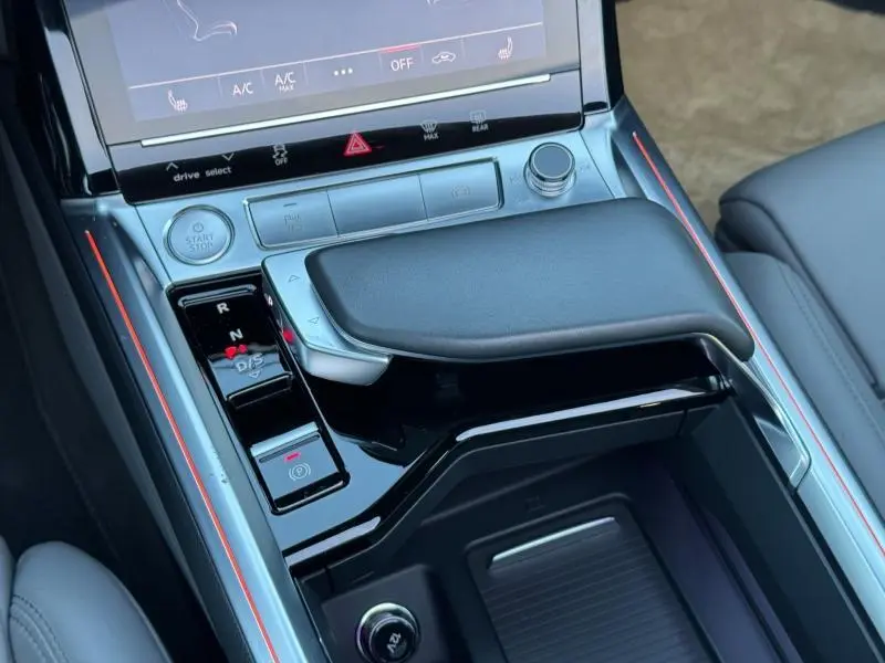 Gros plan sur la console centrale de l'Audi E-Tron Sportback gris foncé, mettant en valeur le levier de vitesses et les commandes tactiles.