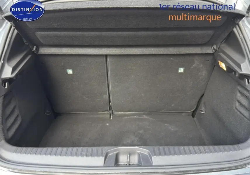 Coffre ouvert de la Renault Clio V gris, vue de l'arrière montrant l'espace de chargement et la banquette rabattable.