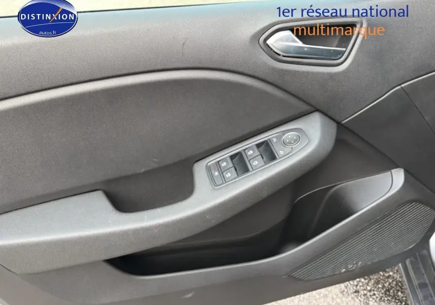 Vue rapprochée de la porte avant gauche de la Renault Clio V gris, montrant les commandes des vitres et haut-parleur intégré.