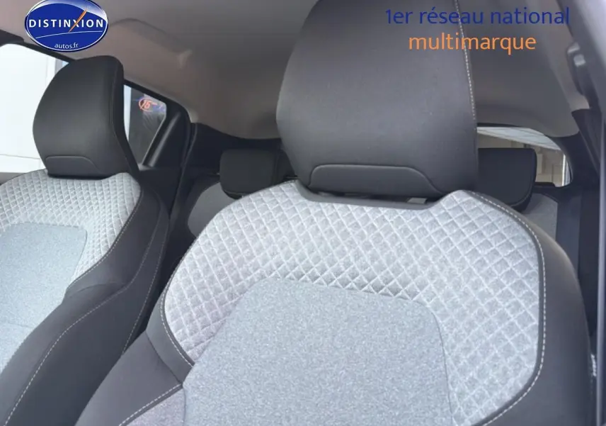 Gros plan sur les sièges avant gris à motif 3D de la Renault Clio V, intérieur textile avec appuie-têtes noirs.