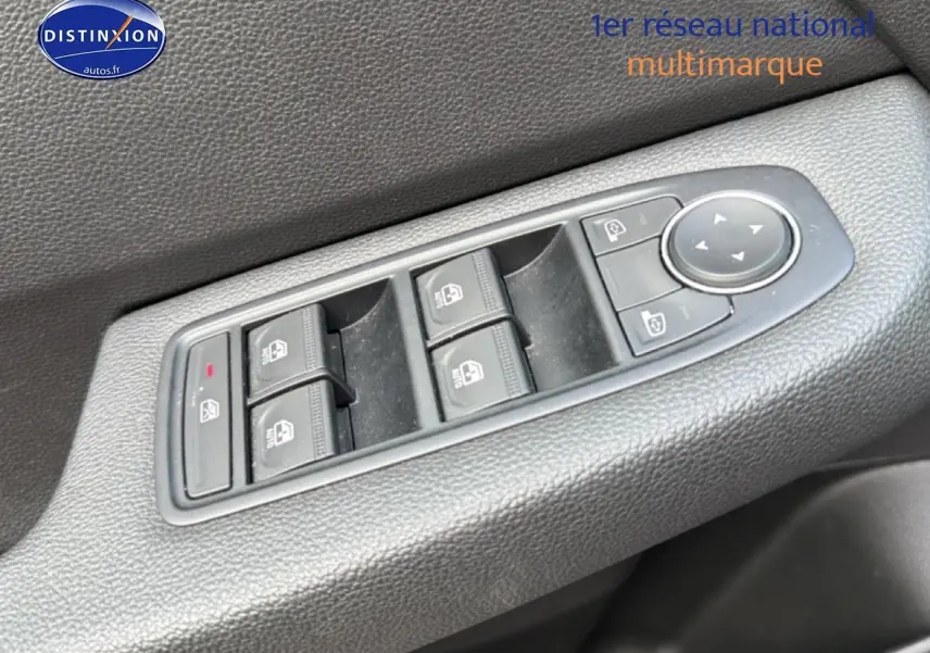 Gros plan sur les commandes de lève-vitres et réglage des rétroviseurs côté conducteur d'une Renault Clio V gris.