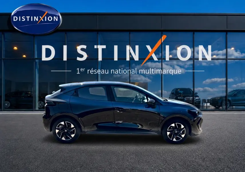Profil latéral droit d'une Renault Clio VI noire 2026, avec jantes alliage et vitres teintées, devant une vitrine Distinxion.