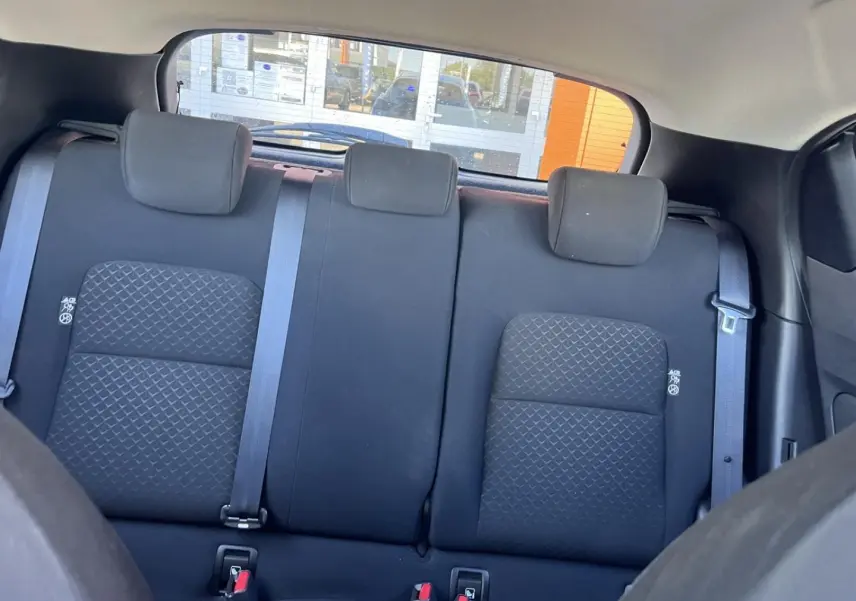 Vue intérieure sur la banquette arrière en tissu noir du Nissan Juke 2023 avec appuis-tête et ceintures de sécurité.