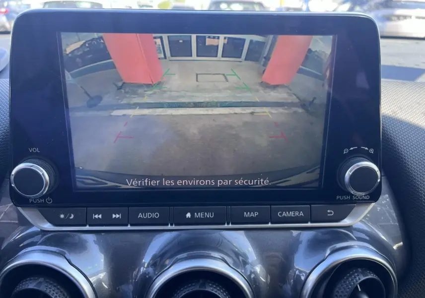 Écran tactile intérieur du Nissan Juke 2023 montrant la caméra de recul avec vue arrière et guidage coloré.