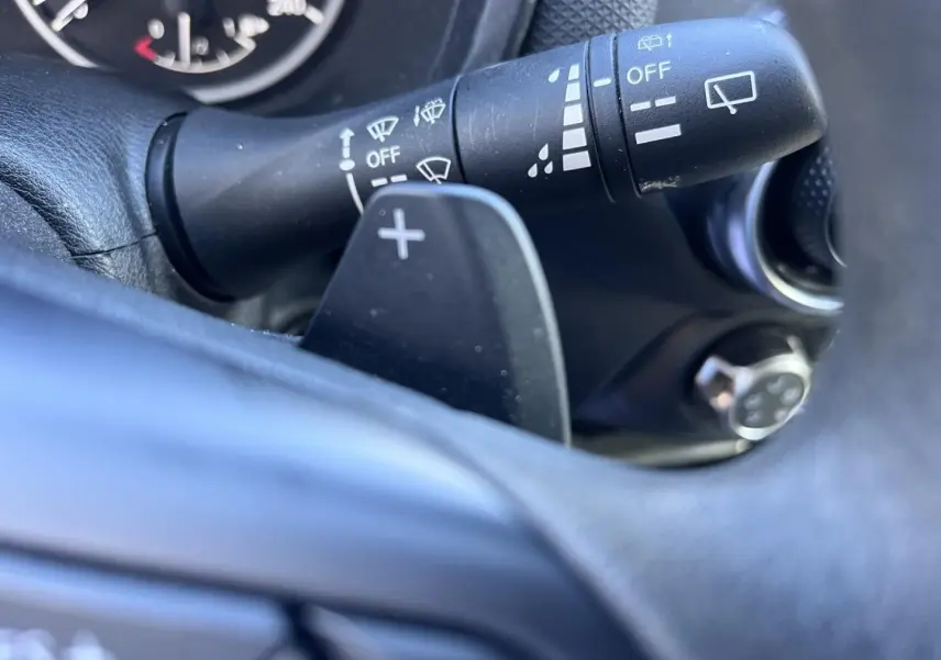 Gros plan sur la commande d'essuie-glace et la palette de changement de vitesse du volant du Nissan Juke 2023.