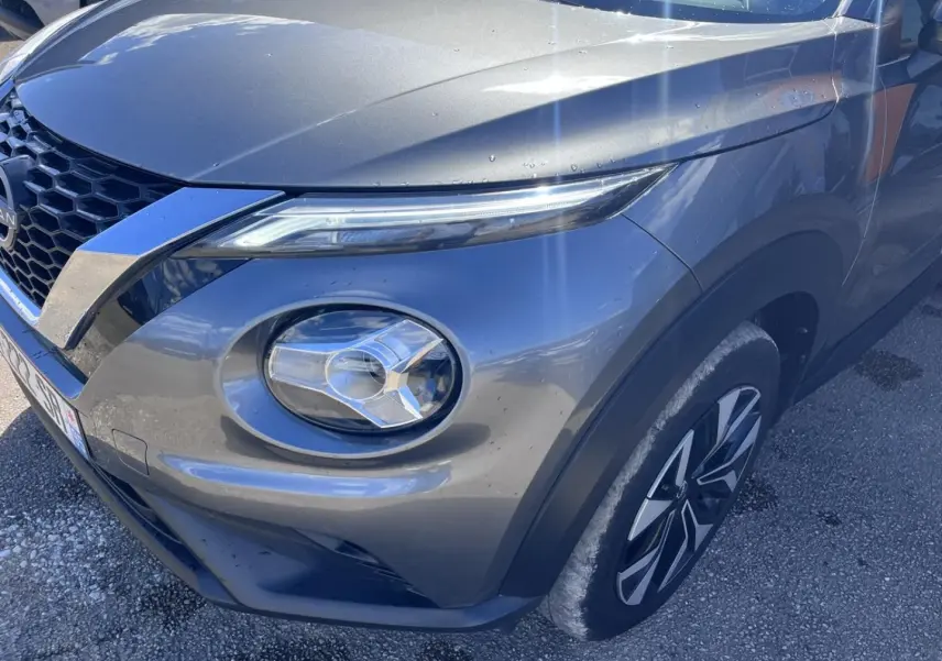 Vue 3/4 avant droit du Nissan Juke 2023 gris Argile Spéciale avec phares LED et jantes bi-ton.