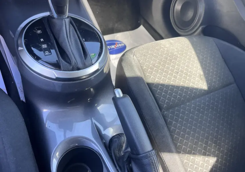 Gros plan sur la console centrale intérieure grise avec levier de boîte auto et siège tissu noir côté passager.