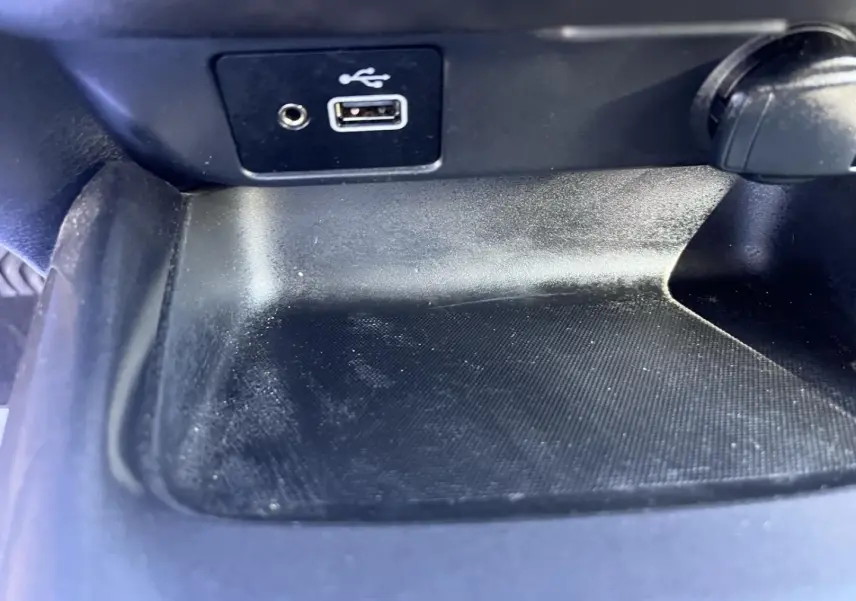 Gros plan sur la prise USB et la prise jack dans le compartiment de rangement intérieur noir du Nissan Juke 2023.