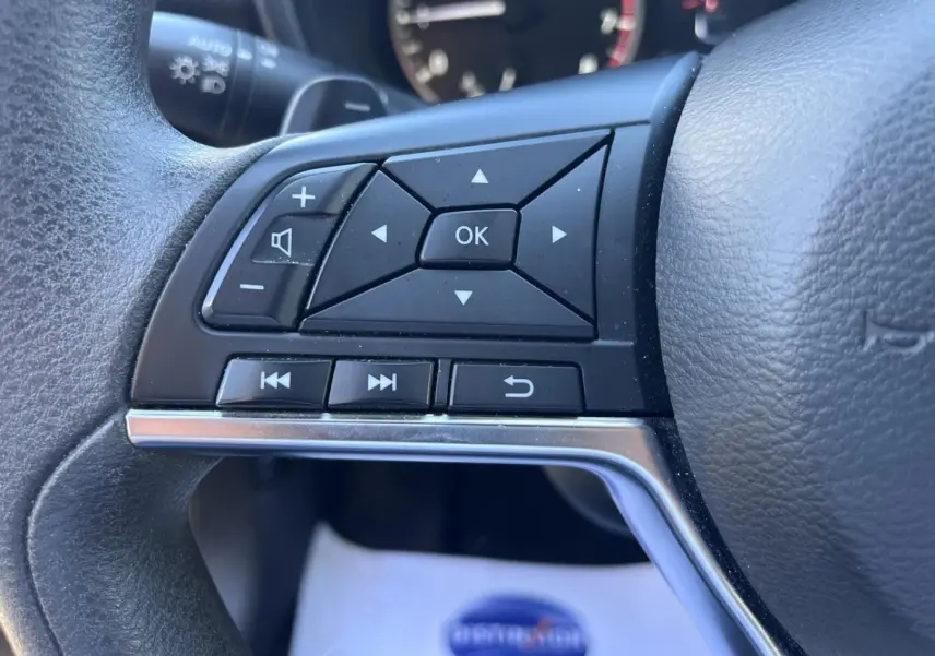 Gros plan sur les commandes multifonctions à gauche du volant du Nissan Juke 2023 en tissu noir.