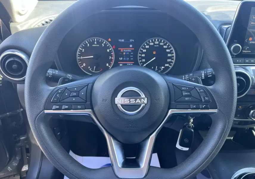 Vue rapprochée du volant multifonction noir et du tableau de bord digital du Nissan Juke 2023 Gris Argile Spéciale.