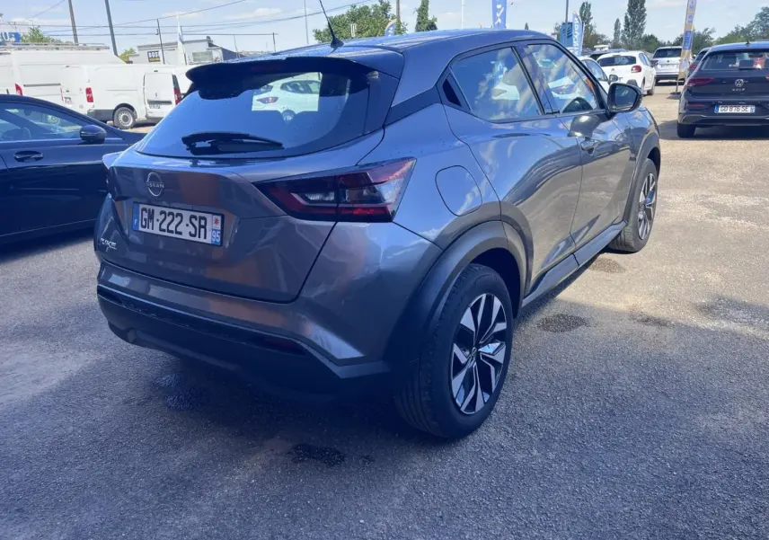 Vue 3/4 arrière droite d'un Nissan Juke 2023 gris argile avec jantes bi-ton et feux arrière LED.