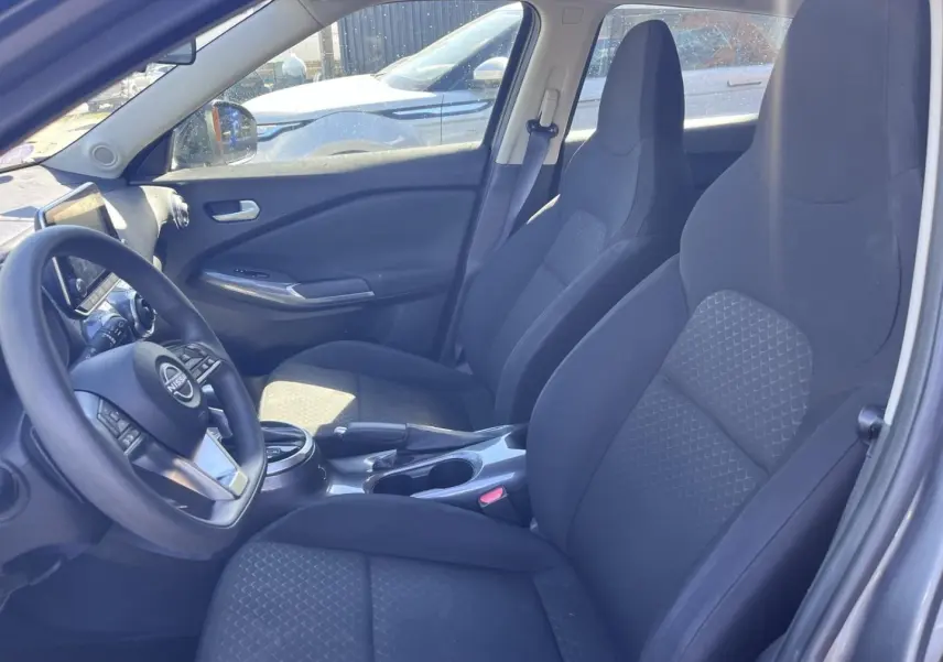 Intérieur avant du Nissan Juke 2023, vue côté conducteur, sièges tissu noir et volant multifonction.