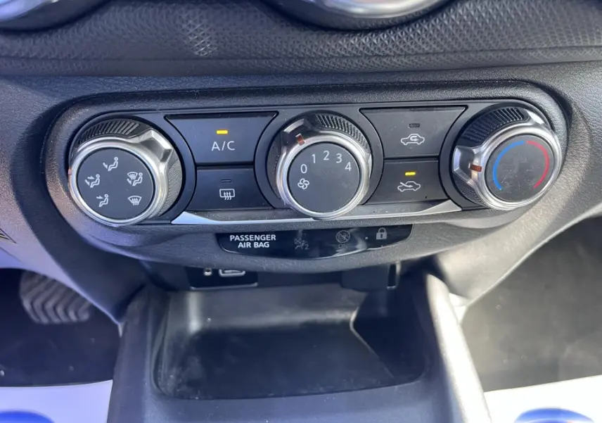 Gros plan sur les commandes de climatisation manuelle du Nissan Juke gris, avec réglages de ventilation et température.