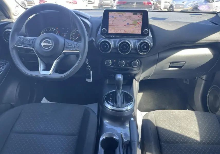 Vue intérieure avant du Nissan Juke 2023 avec tableau de bord noir, écran tactile GPS et volant multifonction.
