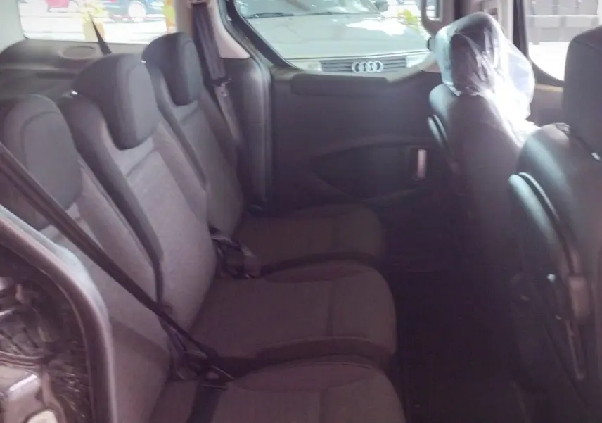 Intérieur arrière du Citroën Berlingo noir 2016, vue côté gauche montrant les trois sièges passagers en tissu gris.