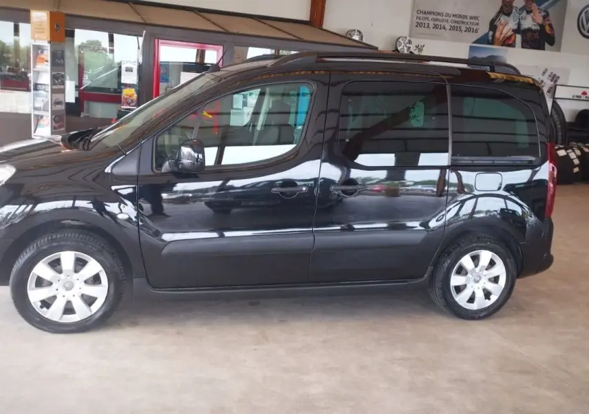 Profil côté gauche d'un Citroën Berlingo noir 2016 en intérieur, soulignant ses lignes compactes et ses jantes argentées.