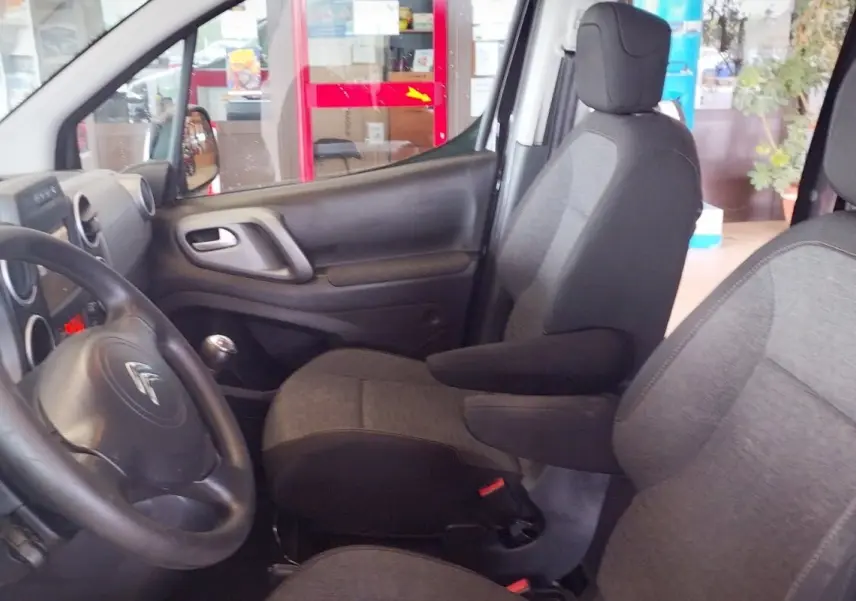 Intérieur avant du Citroën Berlingo 2016 noir, vue côté conducteur avec sièges en tissu gris et volant multifonction.