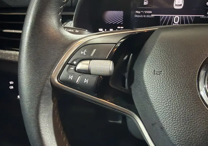 Gros plan sur le volant cuir multifonctions côté gauche du Skoda Kamiq 2024, avec commandes audio intégrées.