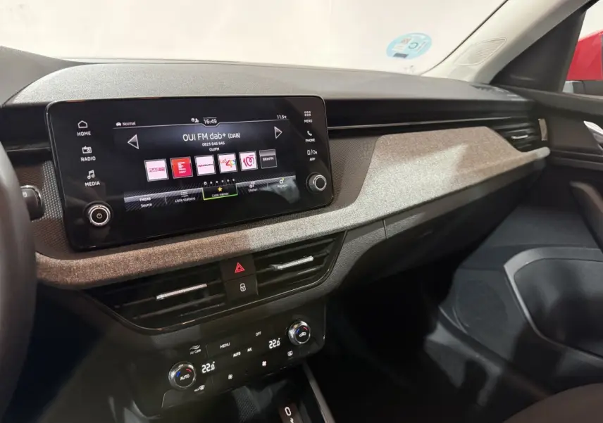 Vue intérieure côté passager du tableau de bord du Skoda Kamiq 2024 avec écran tactile et finition tissu gris clair.