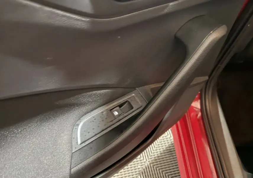 Détail de la porte intérieure côté conducteur d’un Skoda Kamiq rouge avec bouton de verrouillage des vitres.