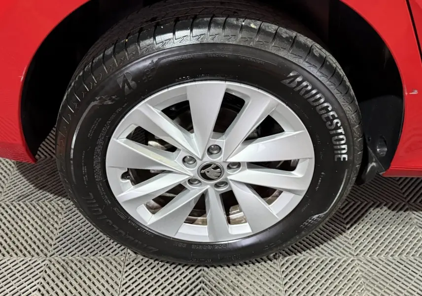 Gros plan sur la roue avant gauche d’une Skoda Kamiq rouge avec jante argentée et pneu Bridgestone.