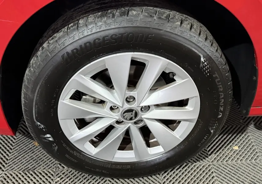 Gros plan sur la roue avant droite d'une Skoda Kamiq rouge, mettant en valeur la jante argentée et le pneu Bridgestone.