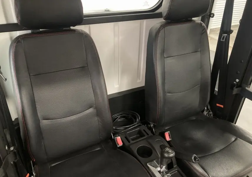 Vue intérieure rapprochée des sièges noirs avec coutures rouges du Liberty L7E H2 160 blanc, version Kit Ridelles.