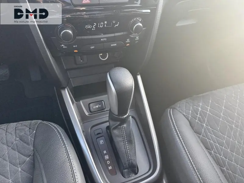 Gros plan sur la console centrale du Suzuki Vitara 1.4 Boosterjet Hybrid, levier de boîte auto et sièges en suédine noire.