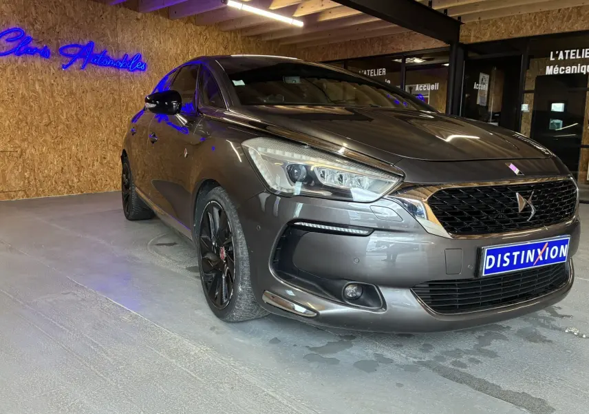 DS5 gris 3/4 avant droit, avec jantes noires et calandre distinctive DS, dans un showroom intérieur.