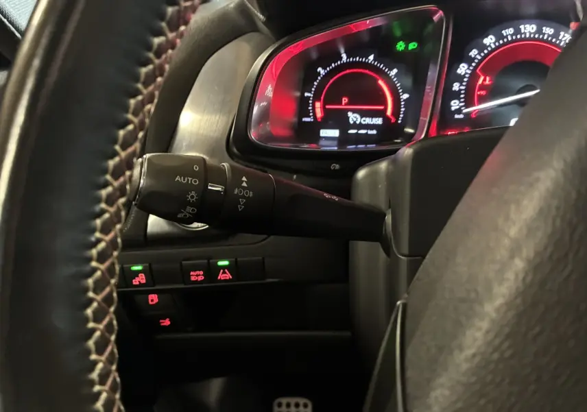 Gros plan sur le tableau de bord et le commodo gauche du DS5 2.0 BlueHDi 180, avec éclairage rouge et commandes visibles.