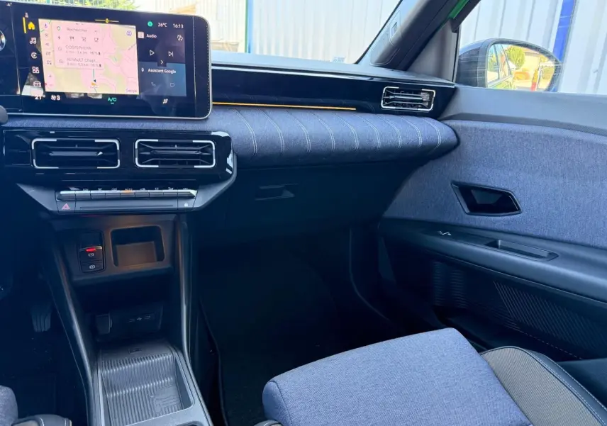 Vue intérieure côté passager de la Renault R5 E-TECH 100% électrique 2024 avec tableau de bord et sellerie textile grise.