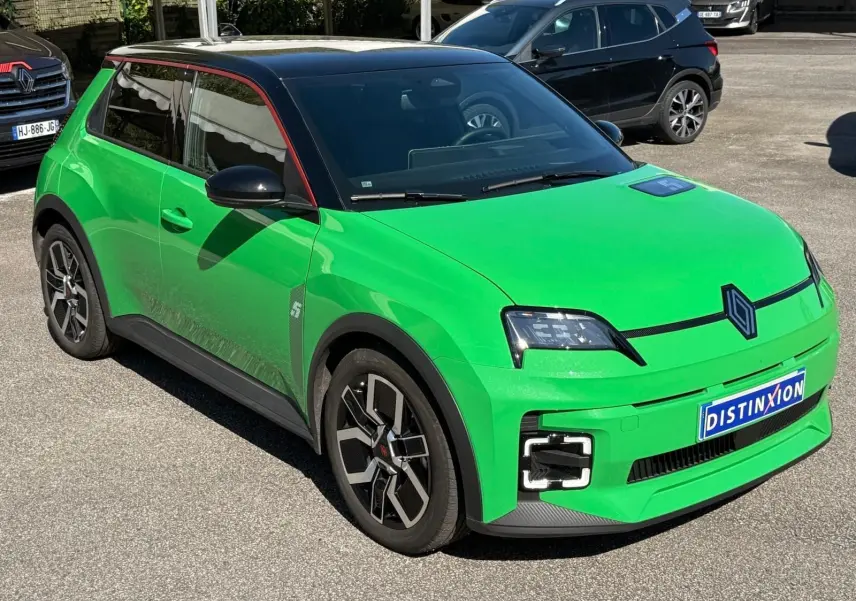 Vue 3/4 avant droit d'une Renault R5 E-Tech électrique vert Pop avec toit noir étoile et jonc de toit rouge alu.