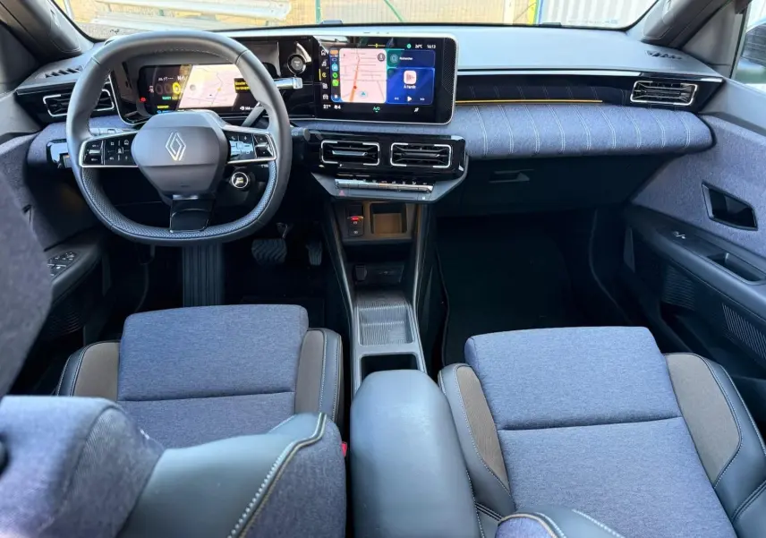 Vue intérieure avant de la Renault R5 E-TECH 100% électrique, avec sellerie textile gris jean et tableau de bord moderne.