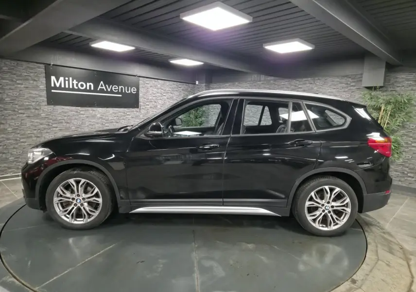 BMW X1 xDrive 25d noir vue de profil côté gauche, avec jantes alliage 18'' style 566 à rayons en Y.